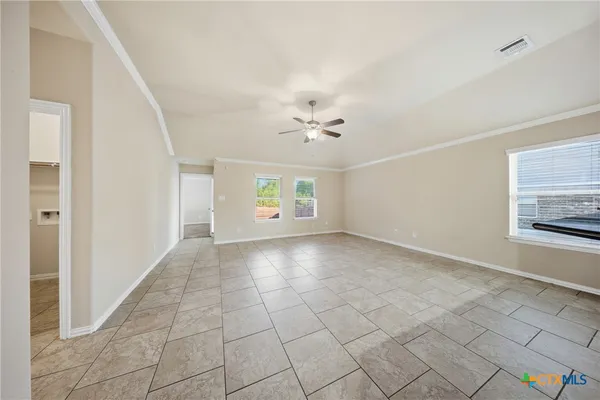 a view of an empty room with kitchen and window
