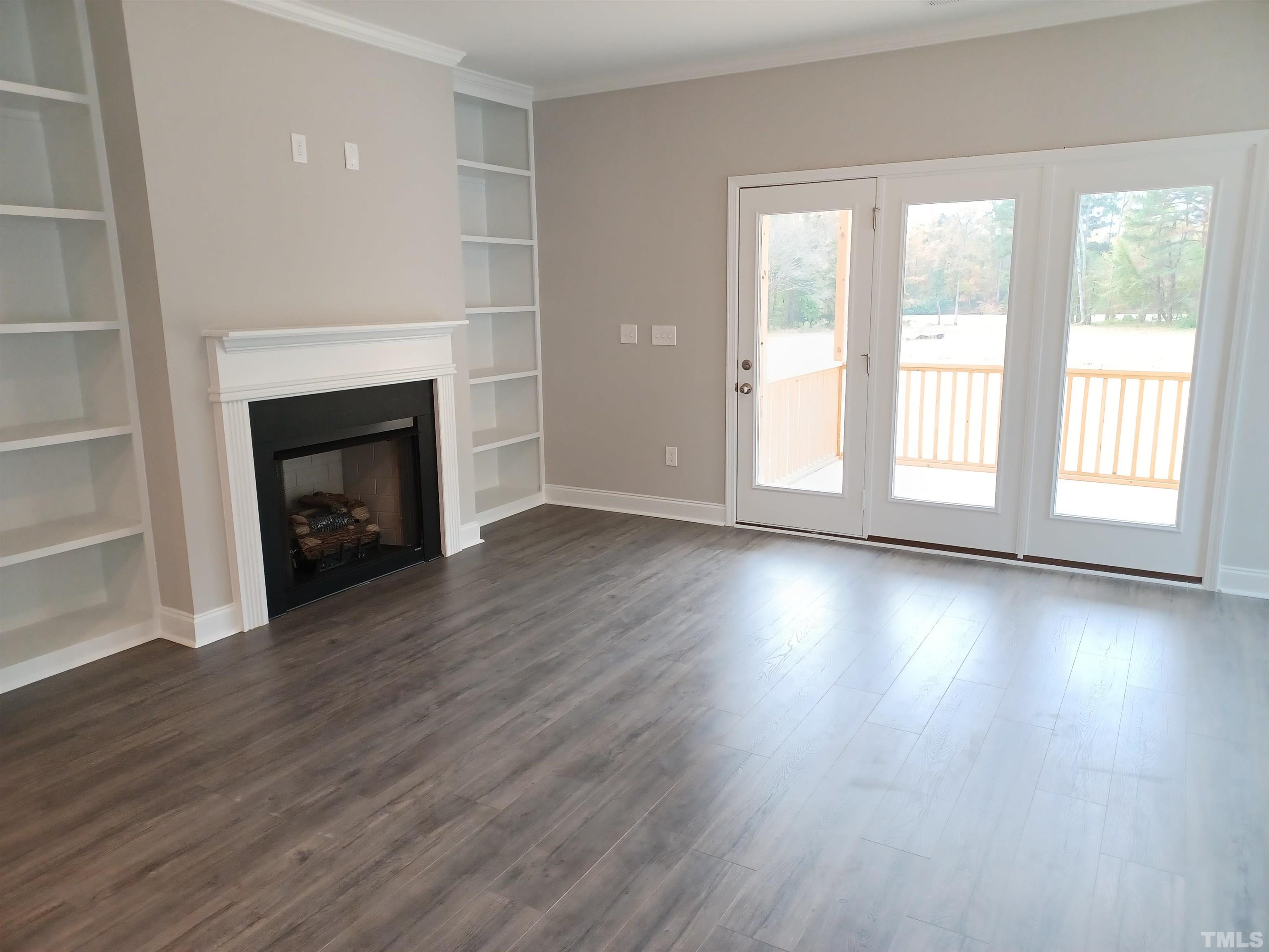 184 Howards Crossing Drive Wendell, NC 27591 - Photo 3 of 27 an empty room with wooden floor fireplace and windows