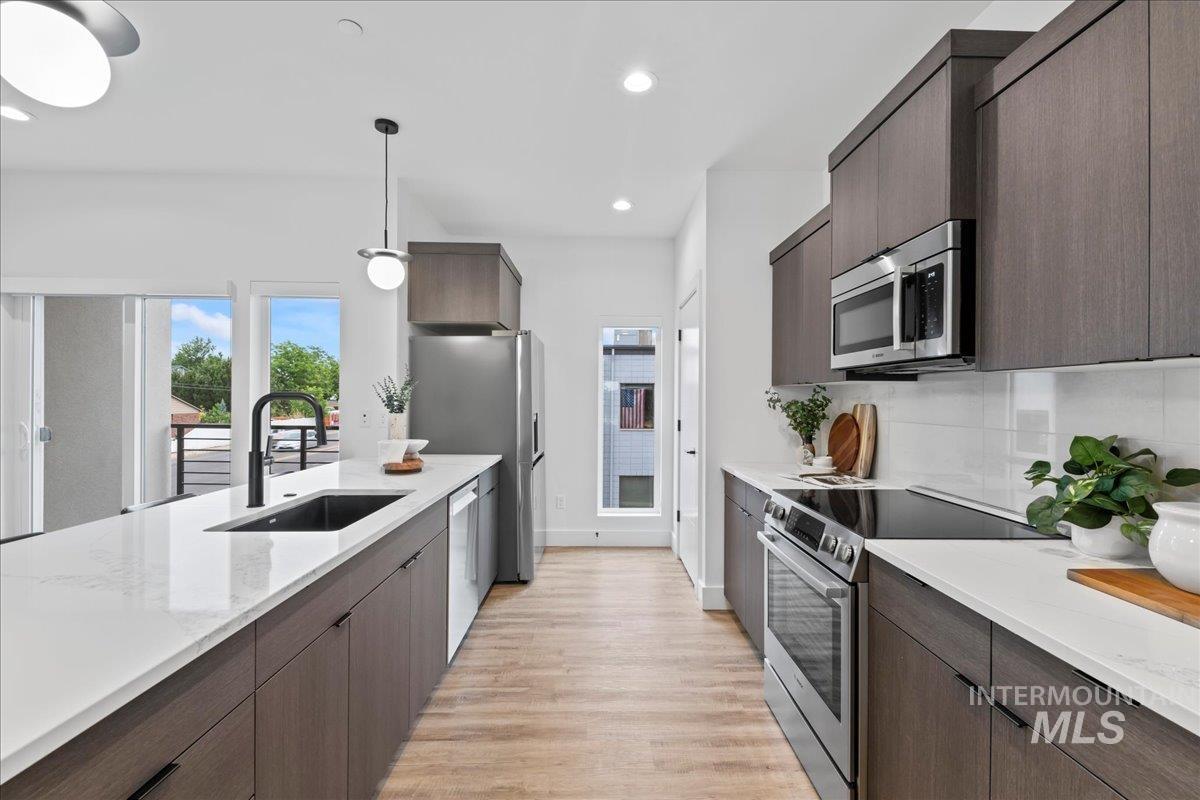 1011 South Orchard Street, Unit 105 Boise, ID 83705 - Photo 2 of 15 Kitchen featuring dark brown cabinets, modern cabinets, stainless steel appliances, light stone counters, and recessed lighting