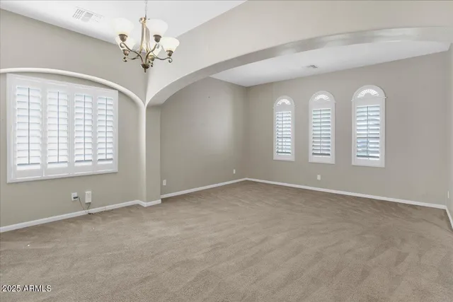 an empty room with windows and chandelier fan