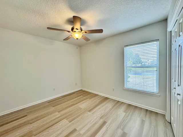 an empty room with a window and ceiling fan