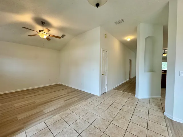 a view of an empty room and chandelier fan