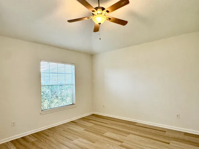 an empty room with a window and a ceiling fan