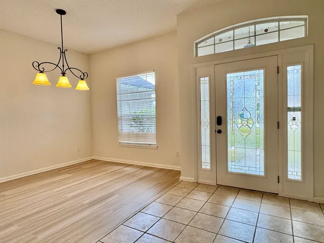 a view of an empty room with window and chandelier fan