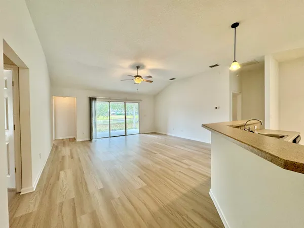 a view of an empty room with window and wooden floor