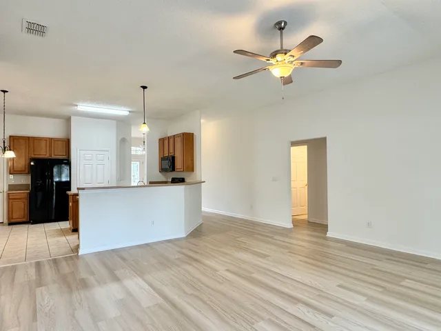 a view of an empty room with kitchen view and a window