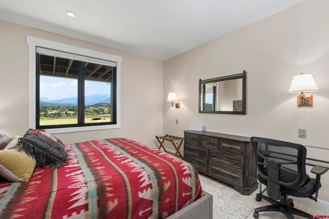 a bedroom with a bed a desk and chair with a mirror