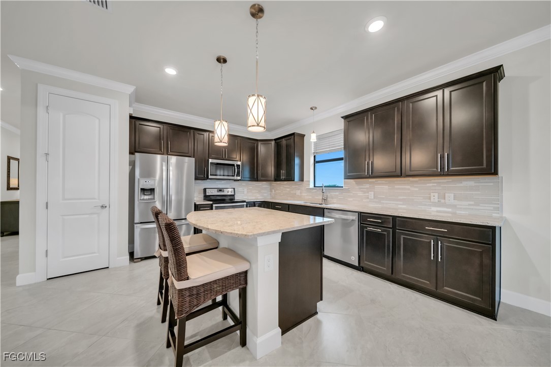 19918 Beverly Park Road Estero, FL 33928 - Photo 6 of 46 a kitchen with stainless steel appliances kitchen island a table chairs in it and a granite counter tops