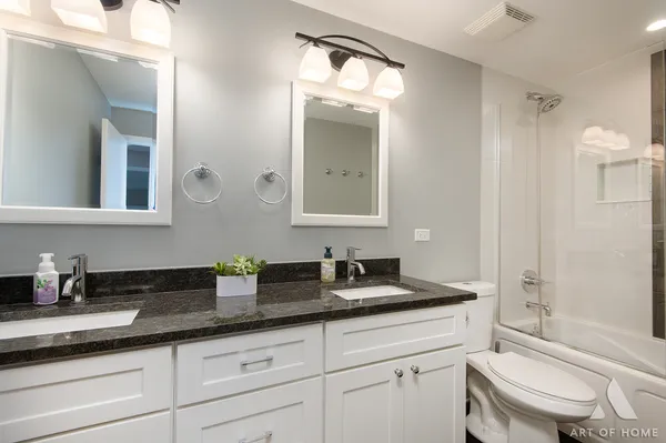 a bathroom with a granite countertop sink a toilet a mirror and shower