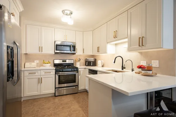 a kitchen with stainless steel appliances granite countertop a stove a sink dishwasher a refrigerator and a microwave with wooden floor