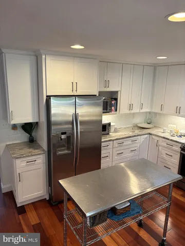 a kitchen with stainless steel appliances granite countertop a refrigerator a sink a stove and white cabinets