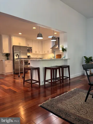 a kitchen with stainless steel appliances granite countertop a stove top oven a dining table and chairs with wooden floor