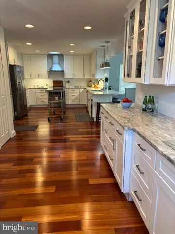 a kitchen with stainless steel appliances granite countertop a stove top oven a sink dishwasher and a refrigerator with wooden floor