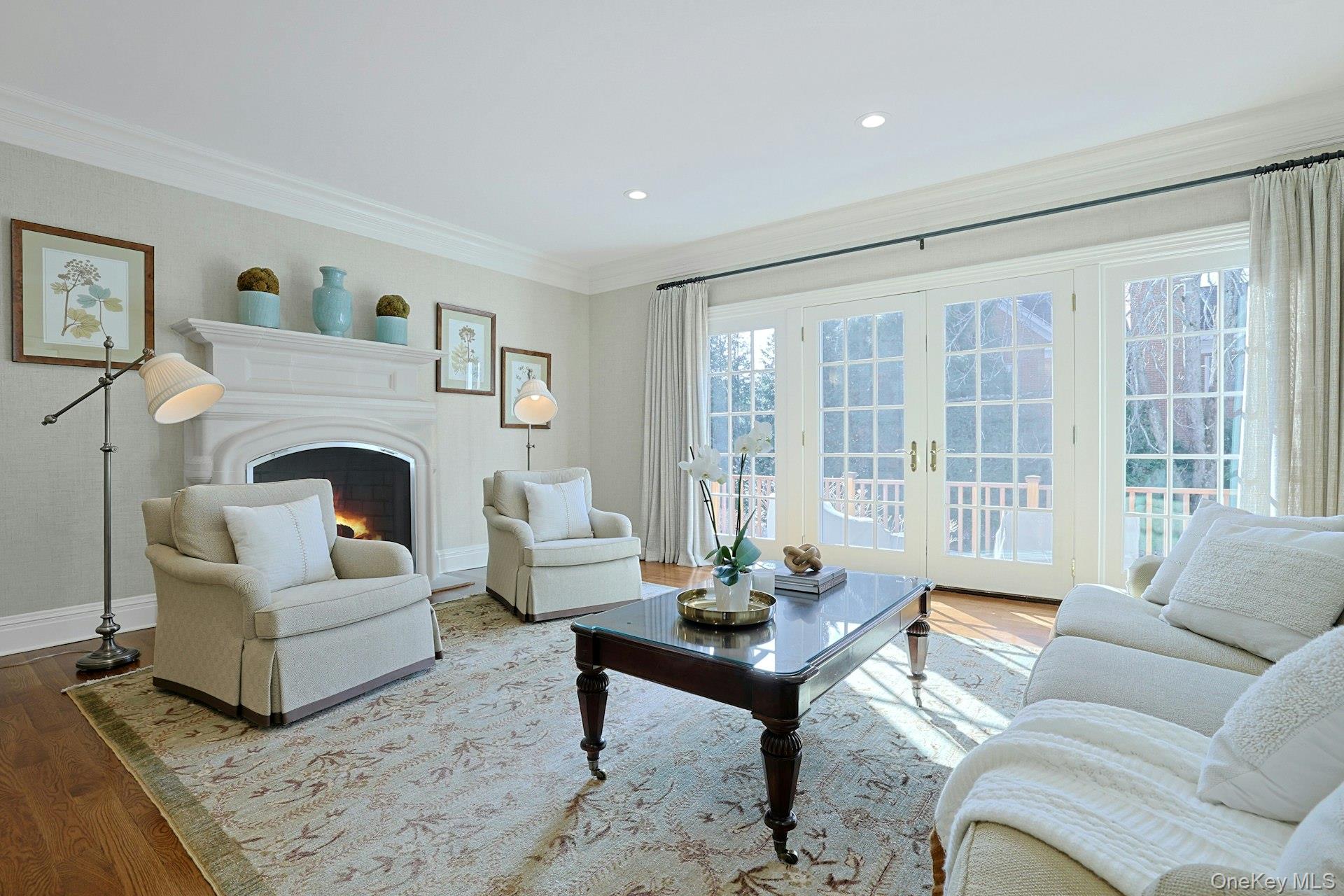 24 Fairview Road Scarsdale, NY 10583 - Photo 13 of 48 Sun-filled family room featuring a limestone fireplace, oversized windows, and French doors that open to the mahogany deck—perfect for everyday living and effortless entertaining.