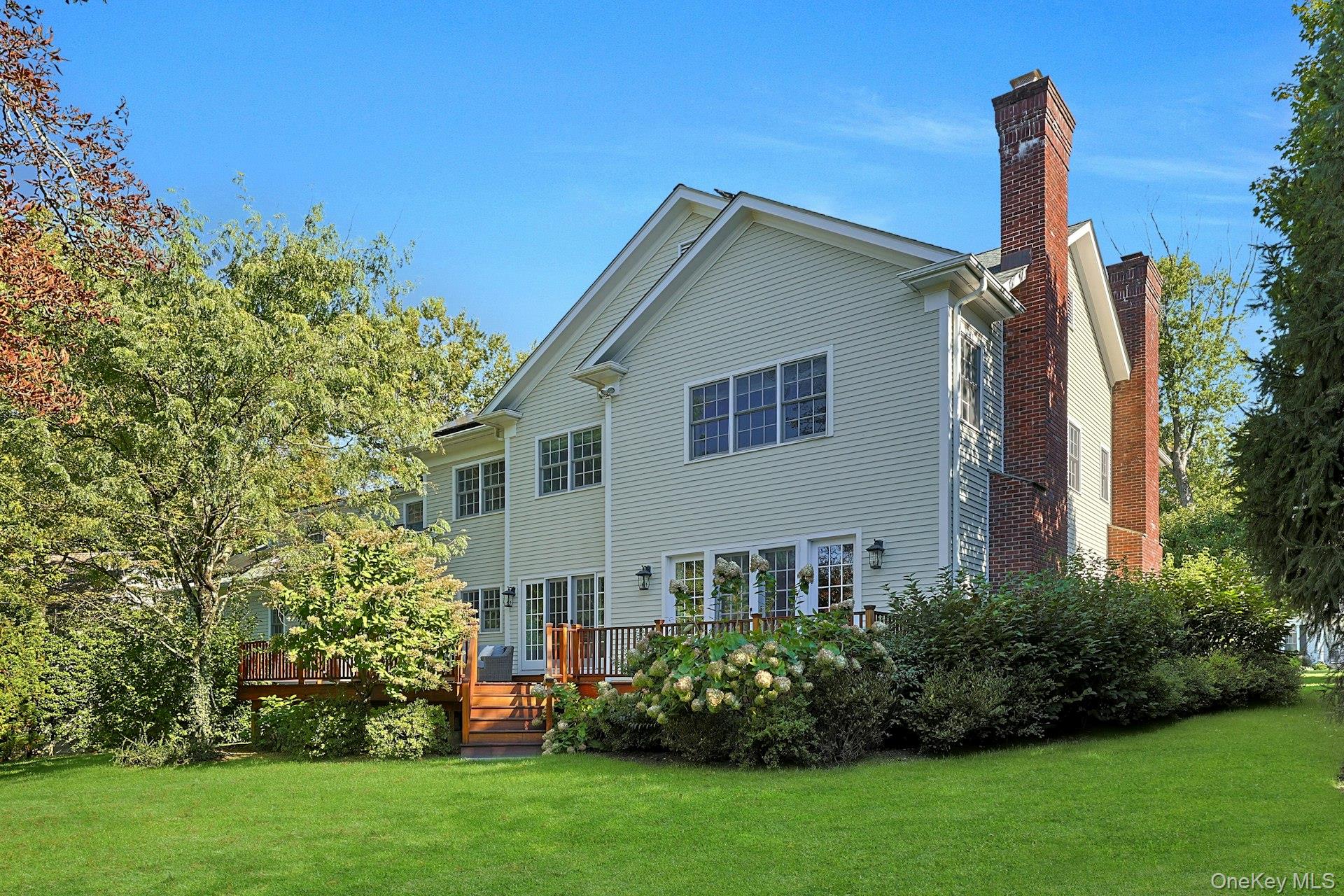 24 Fairview Road Scarsdale, NY 10583 - Photo 44 of 48 Rear exterior highlights the home’s classic architecture, beautiful mahogany deck, and serene backyard setting.