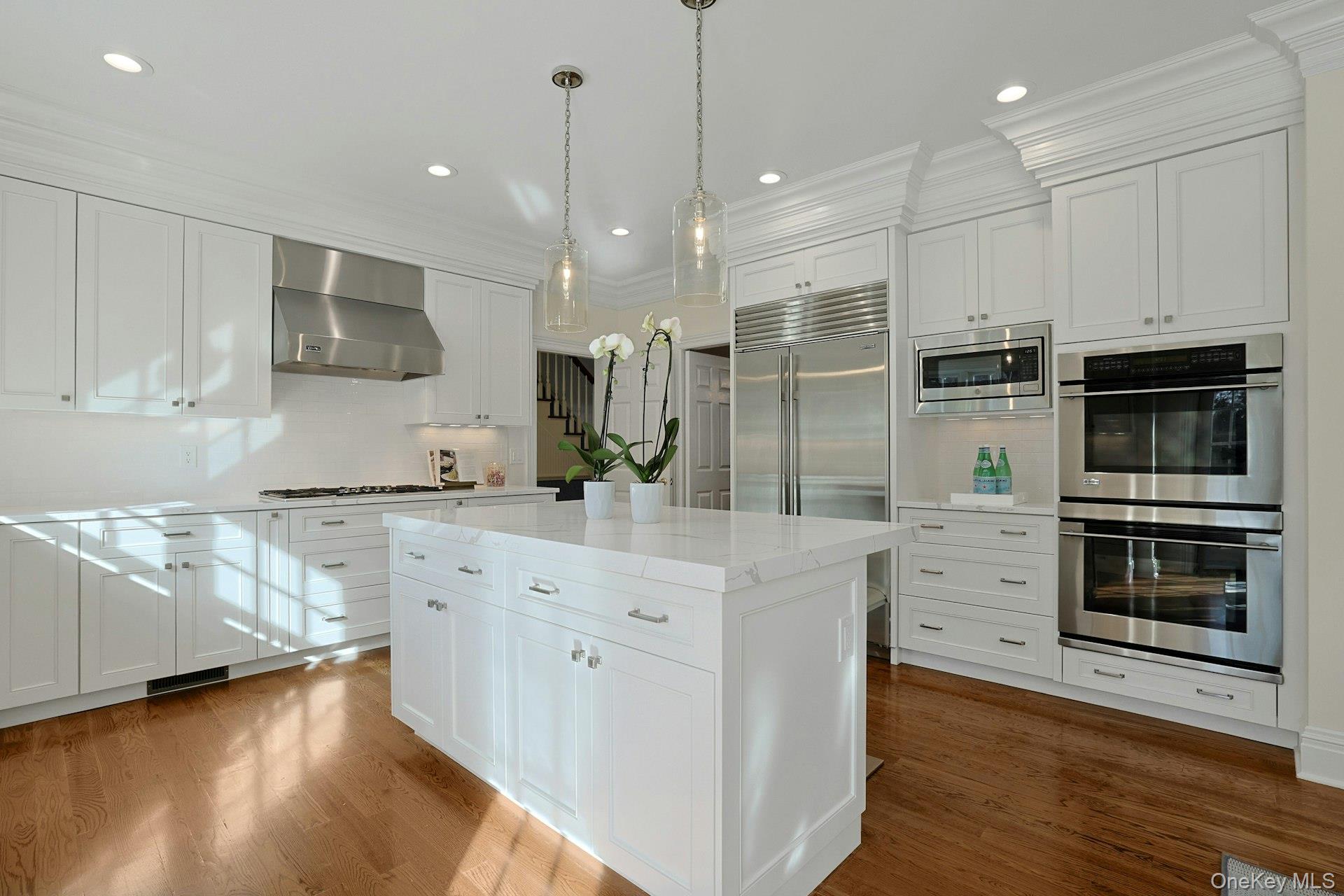 24 Fairview Road Scarsdale, NY 10583 - Photo 9 of 48 A stunning chef’s kitchen featuring custom cabinetry with pullouts, quartzite countertops, a large center island, and premium appliances including a Thermador five-burner gas cooktop with Viking hood and a double GE Monogram ovens —beautifully designed for both everyday living and entertaining.