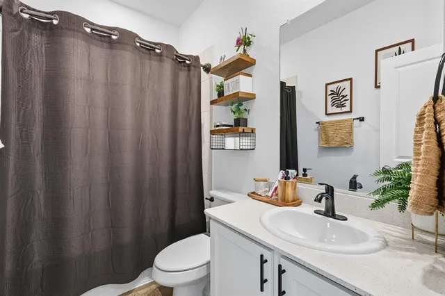 a bathroom with a sink a toilet and shower curtain