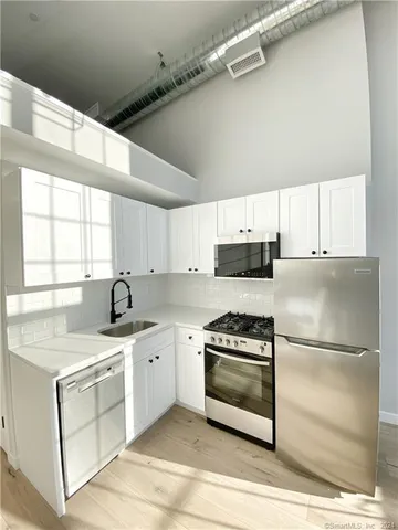 a kitchen with a sink white cabinets and stainless steel appliances