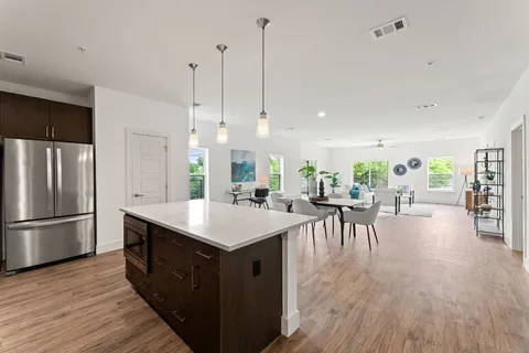 a kitchen with a table chairs refrigerator and wooden floor