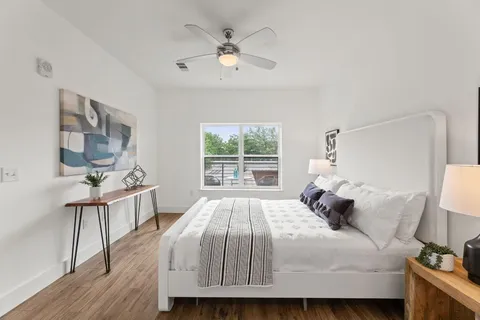 a bedroom with a bed a window and a potted plant on a dresser