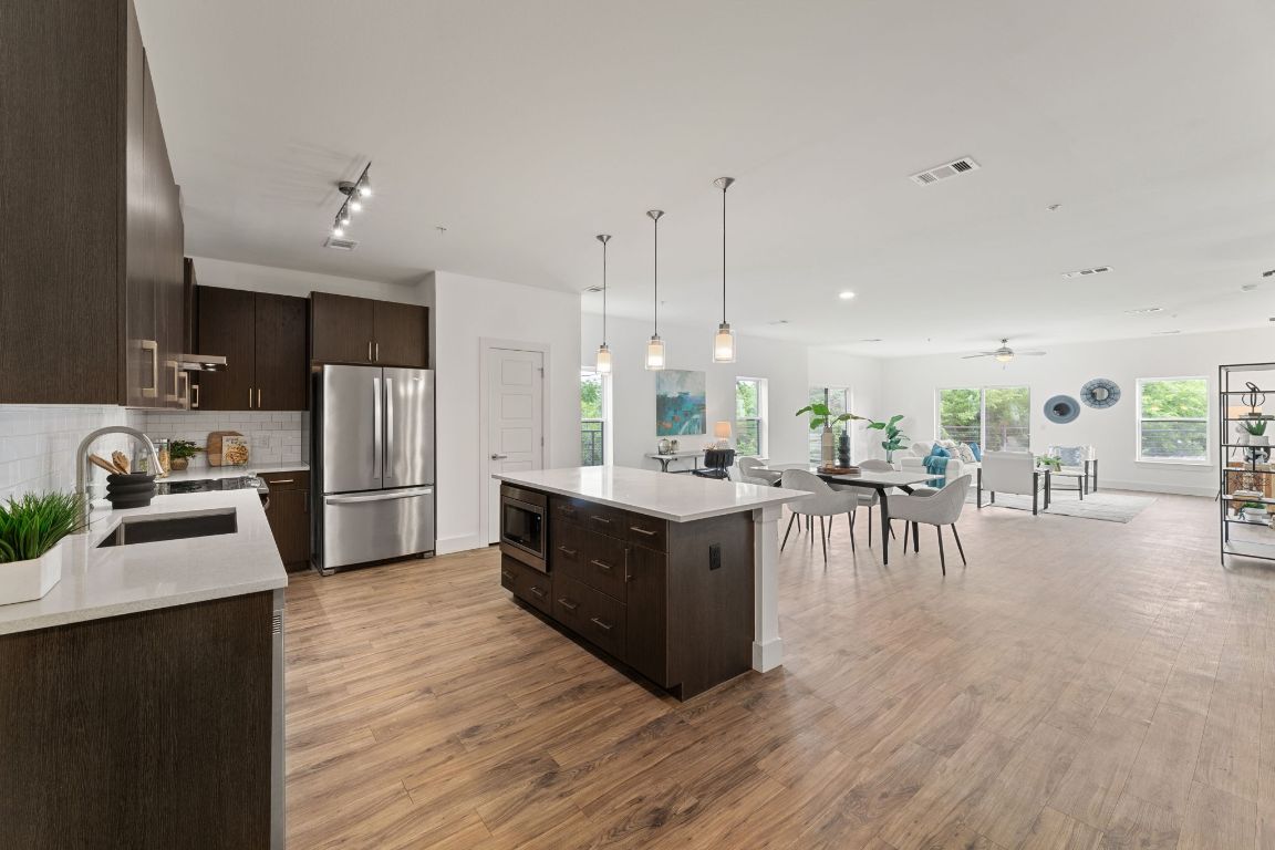 6444 Burnet Road, Unit 204 Austin, TX 78757 - Photo 6 of 36 a kitchen with stainless steel appliances kitchen island granite countertop a stove a refrigerator a sink a dining table and chairs with wooden floor