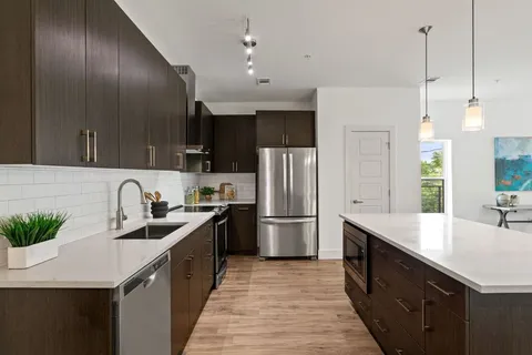 a kitchen with granite countertop a sink a counter space stainless steel appliances and cabinets
