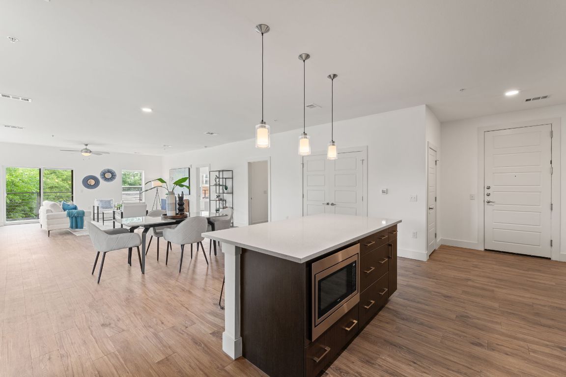 6444 Burnet Road, Unit 204 Austin, TX 78757 - Photo 9 of 36 a kitchen with a table chairs refrigerator and wooden floor