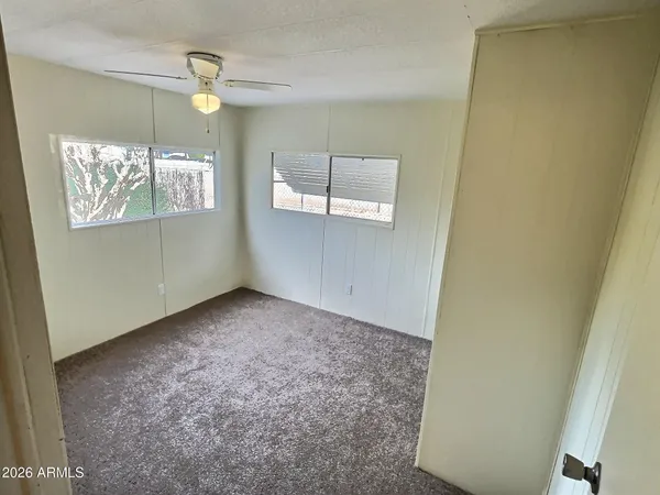 an empty room with windows and fan