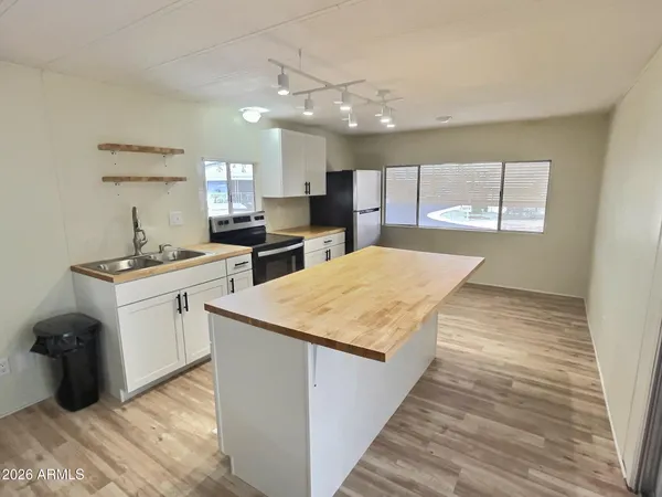 a kitchen with stainless steel appliances granite countertop a sink dishwasher a stove and a refrigerator with wooden floor