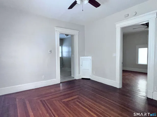 an empty room with wooden floor and a ceiling fan