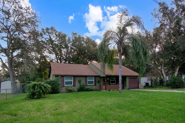 a front view of a house with a garden and trees