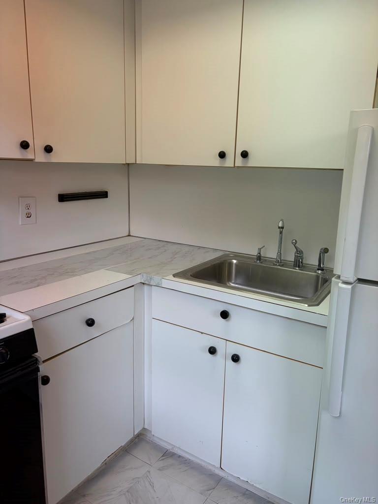 99-60 63rd Road, Unit 1H Queens, NY 11374 - Photo 9 of 11 a kitchen with white cabinets and white appliances