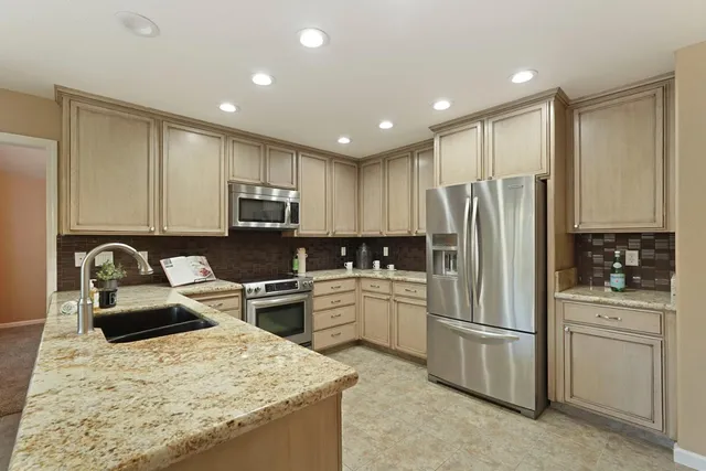 a kitchen with stainless steel appliances granite countertop a stove a sink and a refrigerator