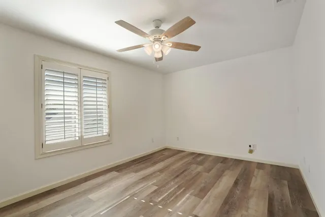 an empty room with a window and a fan