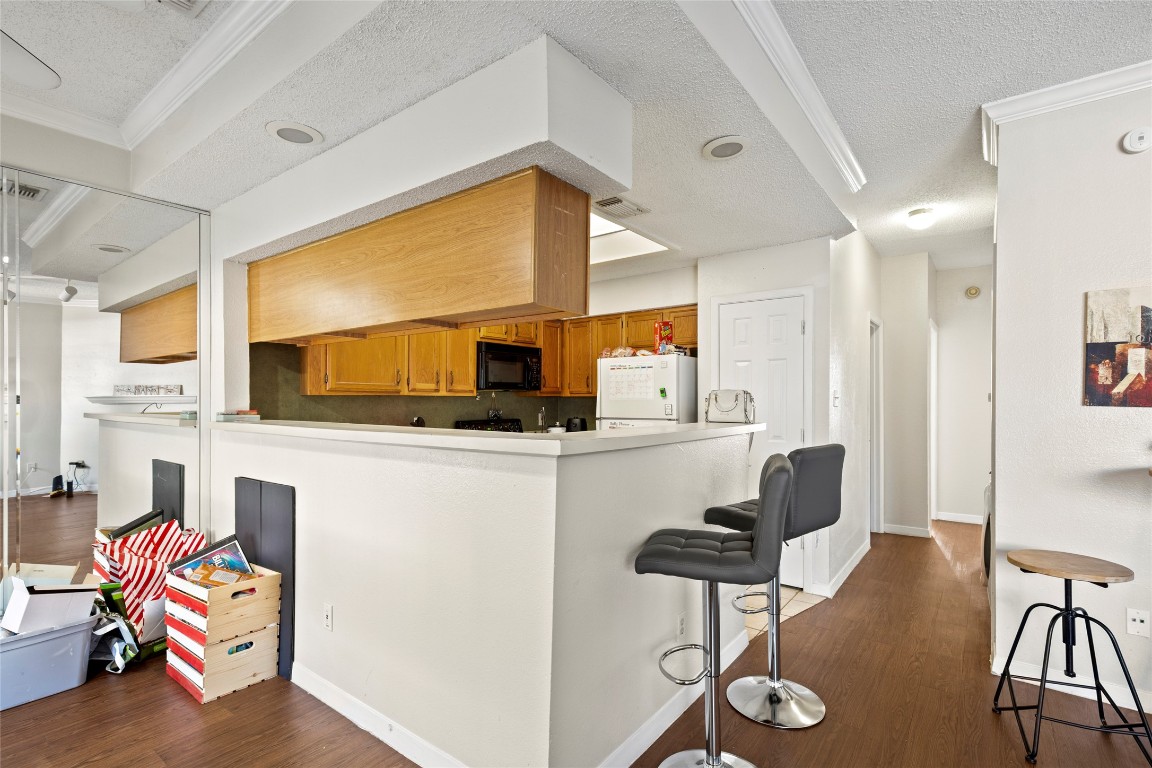 915 West 23rd Street, Unit 208 Austin, TX 78705 - Photo 12 of 16 a kitchen with stainless steel appliances kitchen island granite countertop a table chairs in it and white cabinets