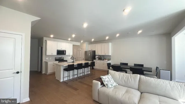 a kitchen with stainless steel appliances kitchen island granite countertop a table chairs and a refrigerator