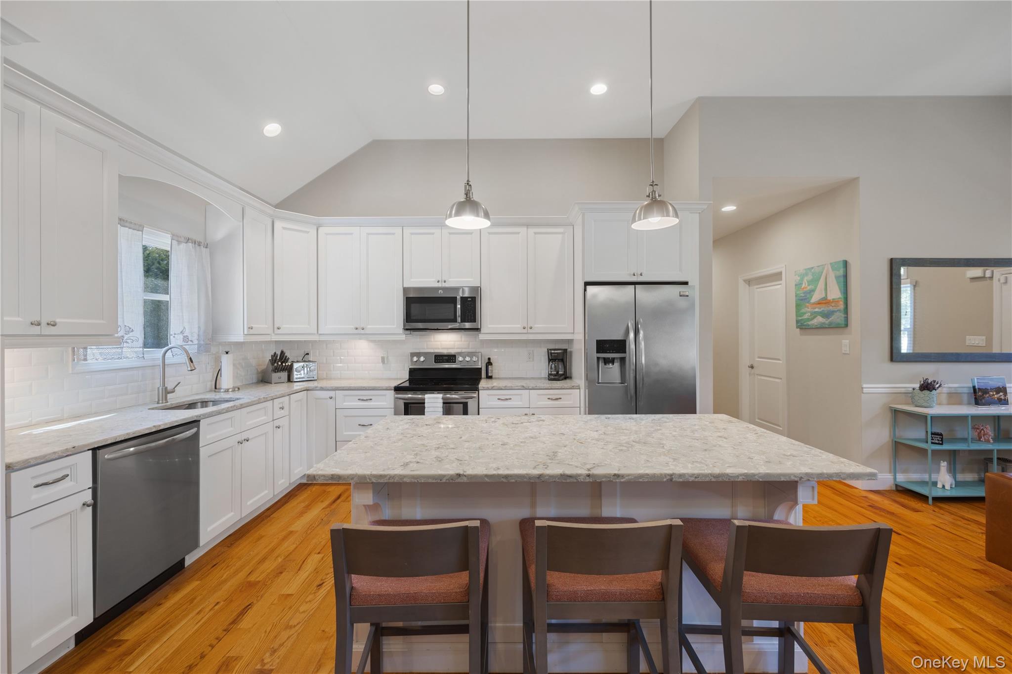 380 Homestead Way Greenport, NY 11944 - Photo 11 of 39 a kitchen with stainless steel appliances granite countertop a table chairs sink refrigerator and microwave