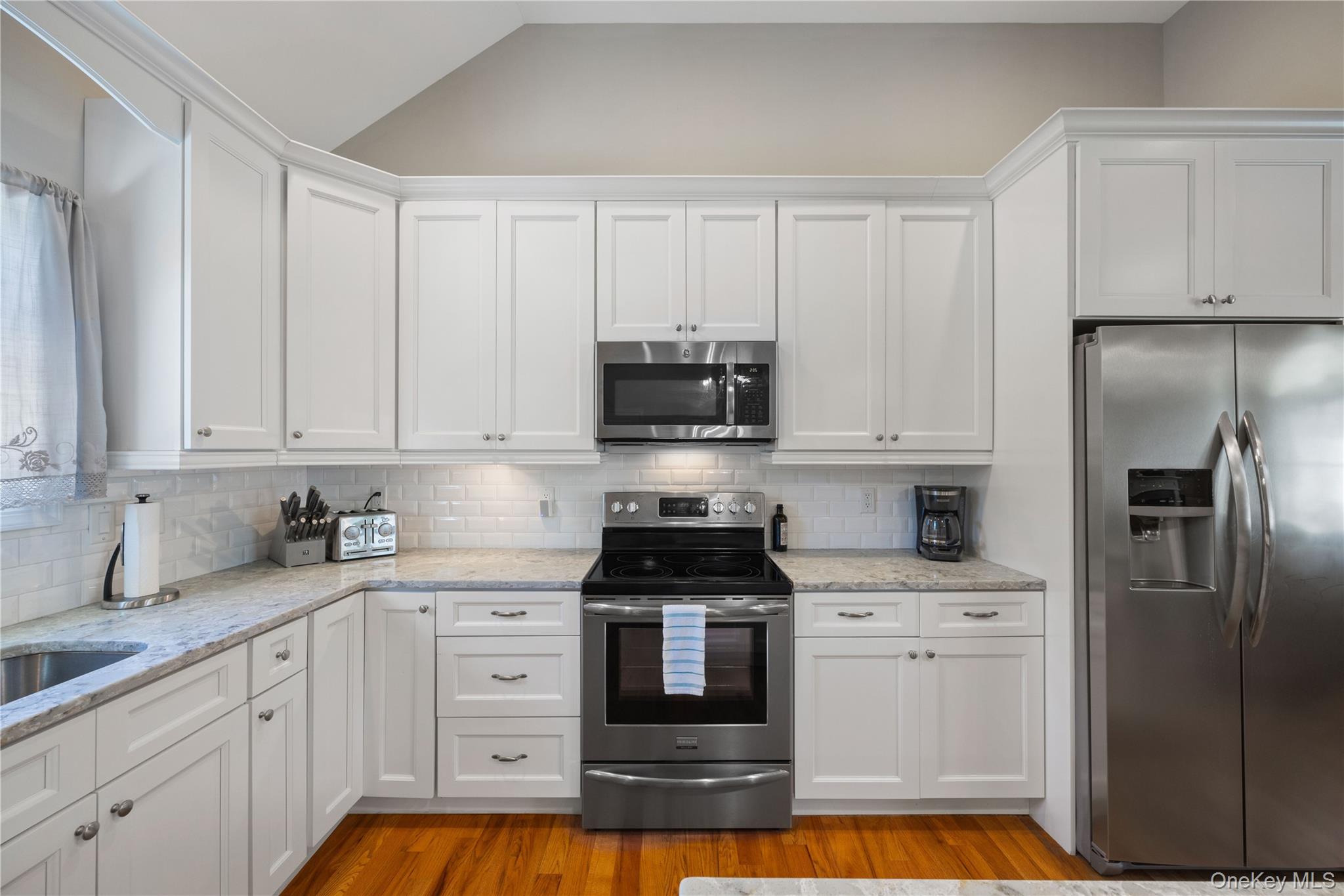 380 Homestead Way Greenport, NY 11944 - Photo 13 of 39 a kitchen with white cabinets and stainless steel appliances