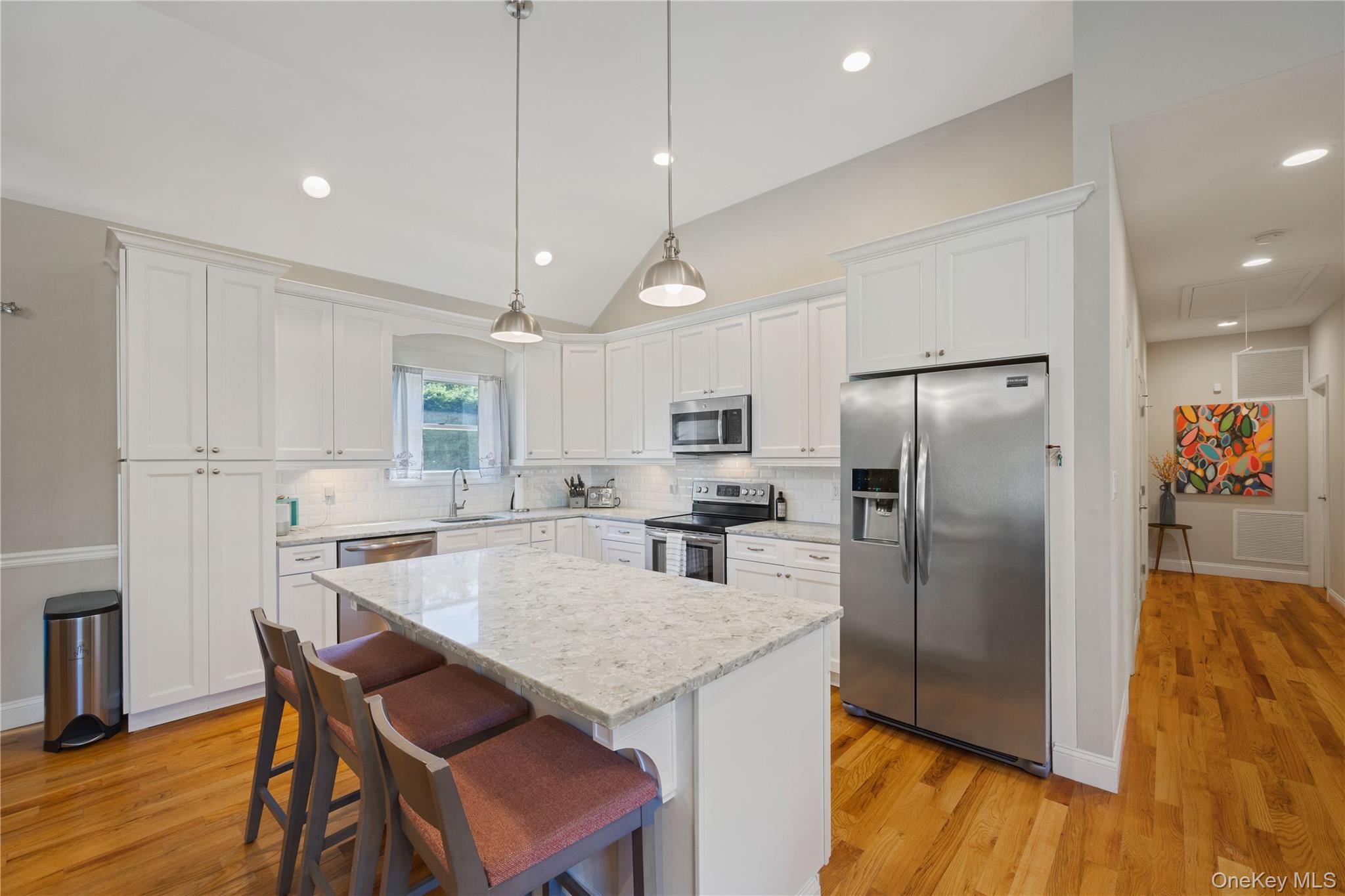 380 Homestead Way Greenport, NY 11944 - Photo 14 of 39 a kitchen with stainless steel appliances granite countertop a refrigerator a stove a sink a dining table and chairs with wooden floor
