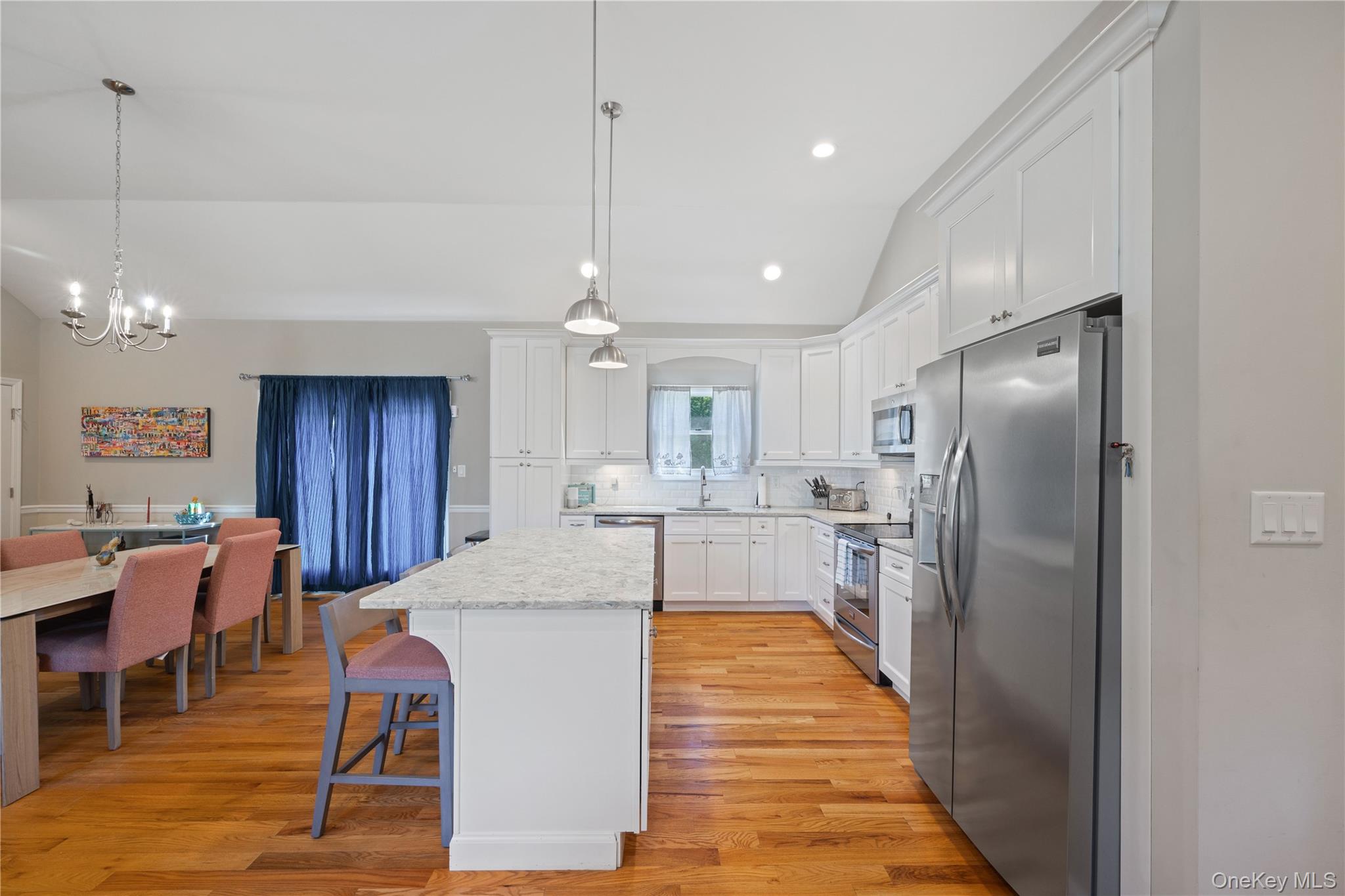380 Homestead Way Greenport, NY 11944 - Photo 10 of 39 a kitchen with stainless steel appliances kitchen island granite countertop a refrigerator a stove a kitchen island a dining table and chairs with wooden floor