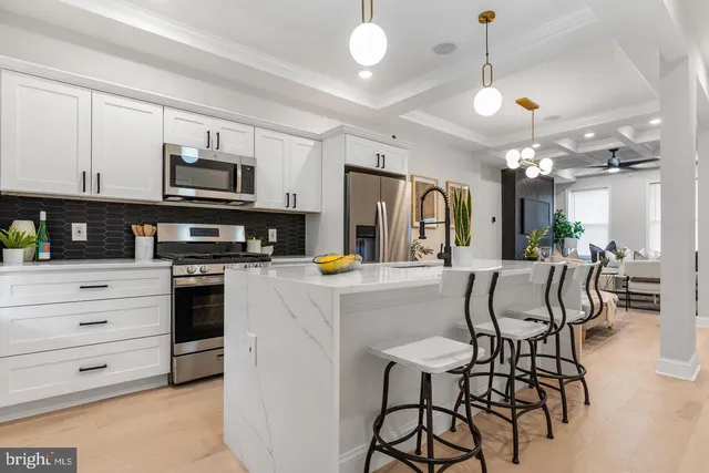 a kitchen with stainless steel appliances a refrigerator a stove a dining table and chairs with wooden floor