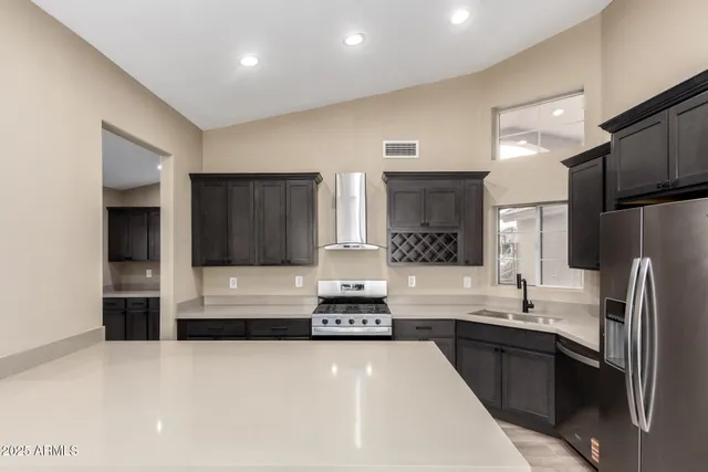 a kitchen with granite countertop a refrigerator stove and sink