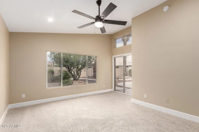 an empty room with windows and fan