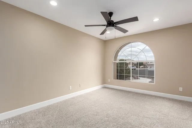 an empty room with a window and a ceiling fan