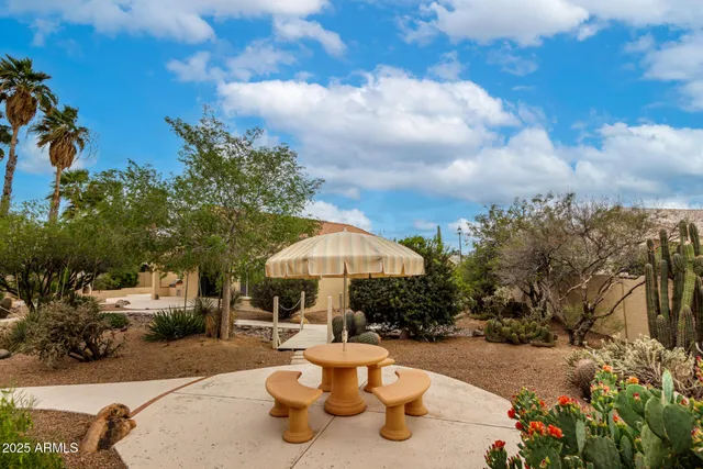 a view of a patio with chairs and a table and chairs under an umbrella