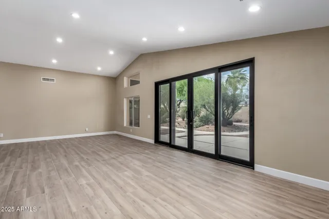 an empty room with wooden floor and windows
