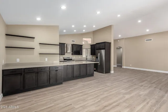 a large kitchen with stainless steel appliances a large counter top a stove a sink and a refrigerator