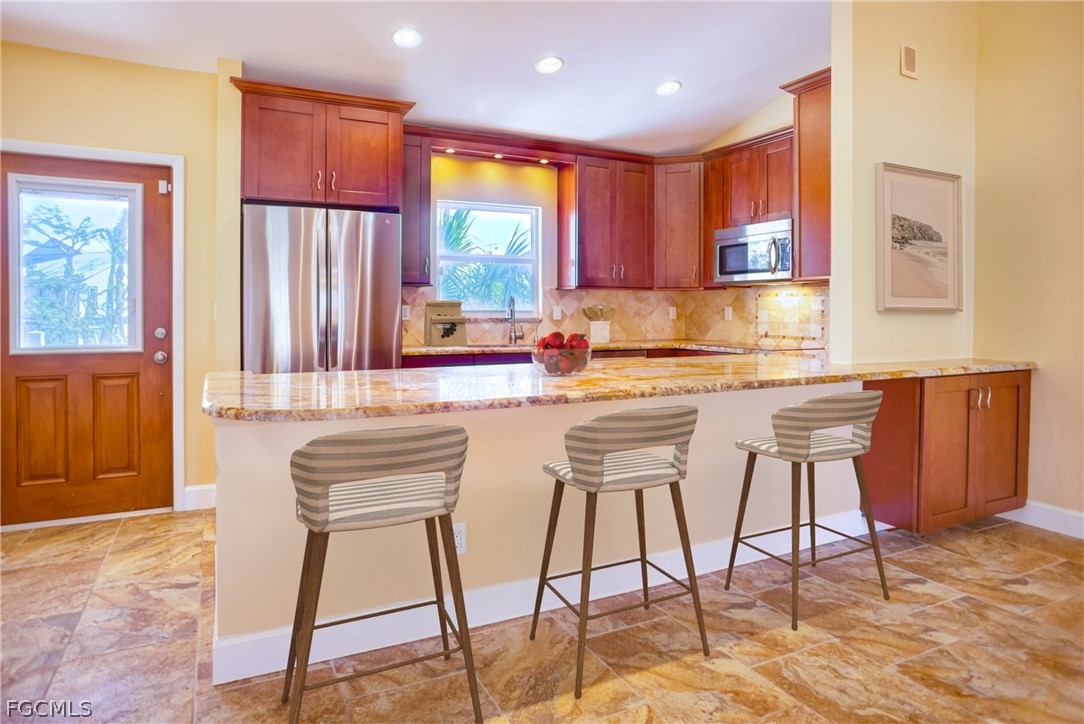 1813 Long Point Lane Sanibel, FL 33957 - Photo 7 of 38 a kitchen with stainless steel appliances kitchen island granite countertop wooden cabinets and dining table chairs