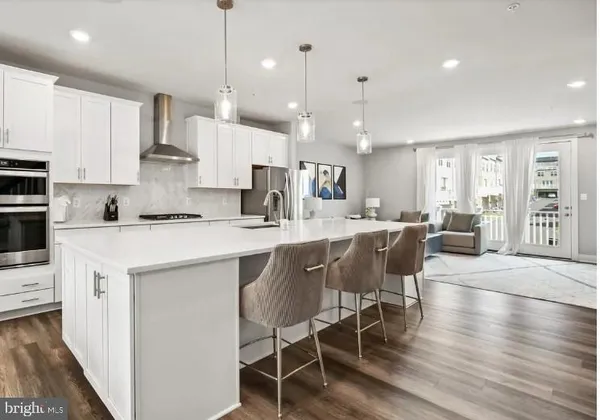 a kitchen with stainless steel appliances kitchen island granite countertop a table chairs sink and cabinets