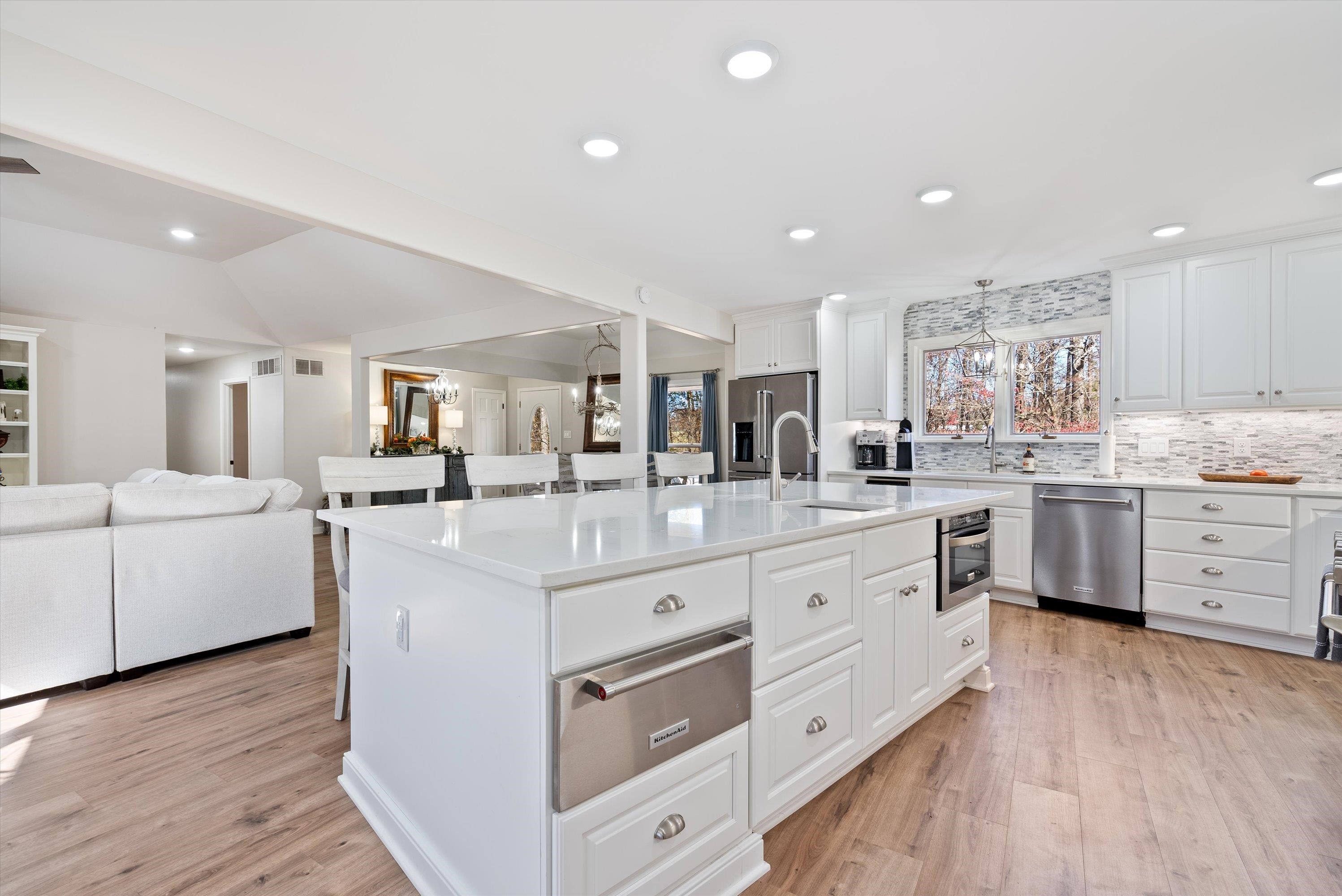a large white kitchen with kitchen island white cabinets and stainless steel appliances